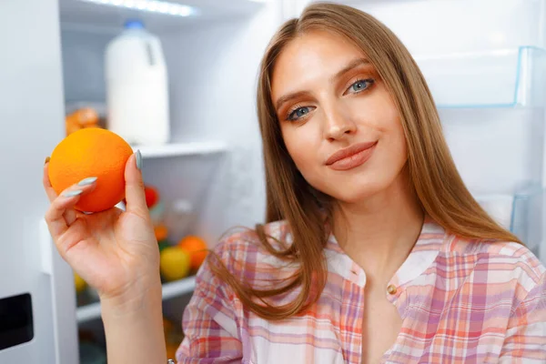 Retrato de una joven rubia tomando comida de su nevera — Foto de Stock