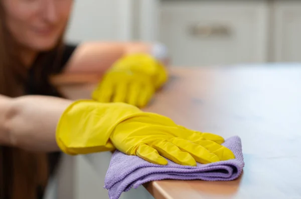 Unrecognizable woman in yellow gloves wiping wooden table top — Stock Photo, Image