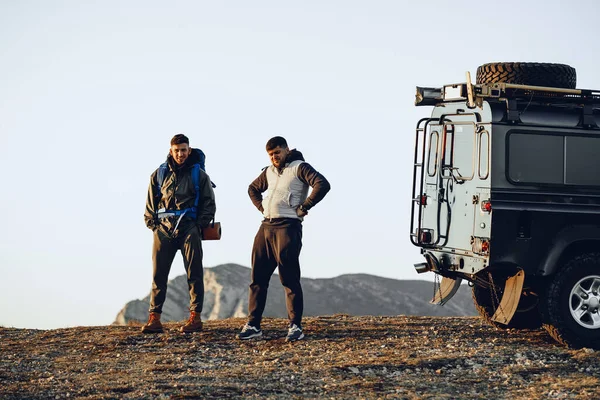 Deux hommes randonneurs debout près de la voiture hors route se préparent à commencer leur voyage — Photo