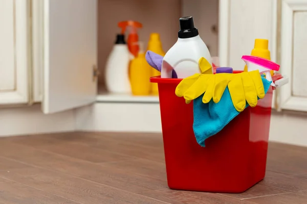 Various household cleaning detergents and bottles in a plastic bucket on the floor — Stock Photo, Image