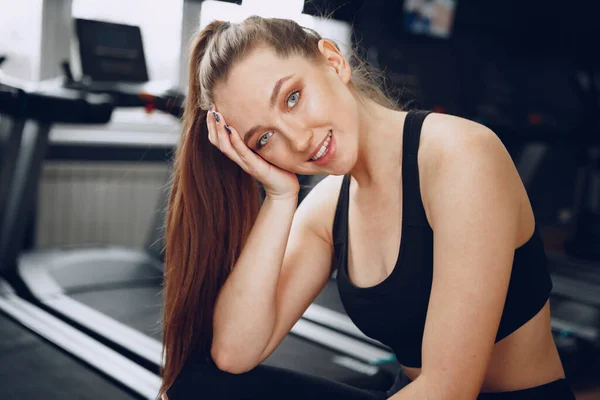 Молода жінка, яка стомилася в спортзалі після тренувань. — стокове фото