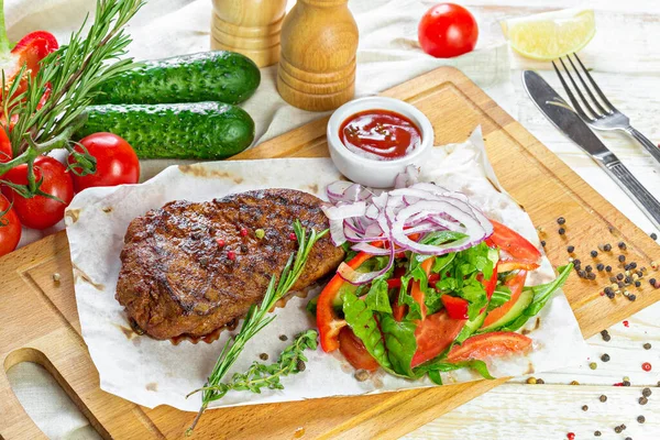 Grilovaný hovězí steak se zeleninovým salátem a omáčkou na dřevěné desce — Stock fotografie