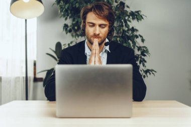 Kulaklık takan genç adam laptopla video görüşmesi yapıyor.