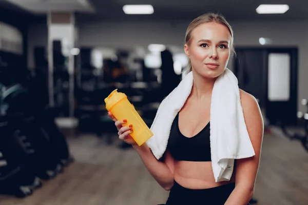 운동하는 젊은 여자가 운동 후 체육관에서 술을 마시고 있다 — 스톡 사진