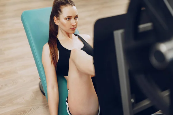 Adatta donna che allena le gambe in un attrezzo da palestra nel fitness club — Foto Stock