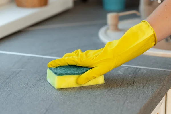 Mujeres manos en guantes amarillos encimera de limpieza en la cocina — Foto de Stock