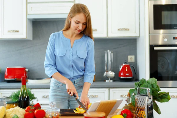 年轻美丽的高加索女人在厨房做饭和使用她的数码平板电脑 — 图库照片