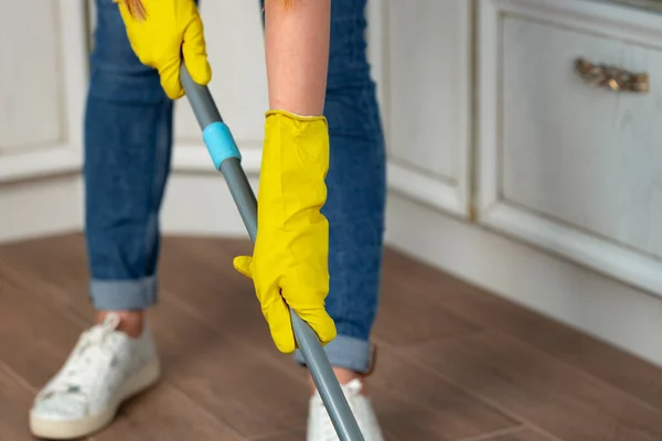 Woman washing floor with mop in kitchen