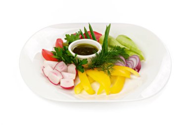 Dilimlenmiş taze sebzeler ve beyaz arka planda sos.