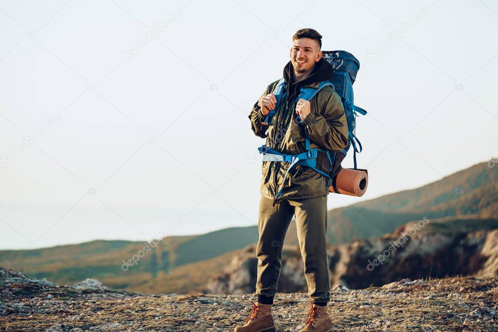 Young caucasian man traveler with big backpack hiking in the mountains