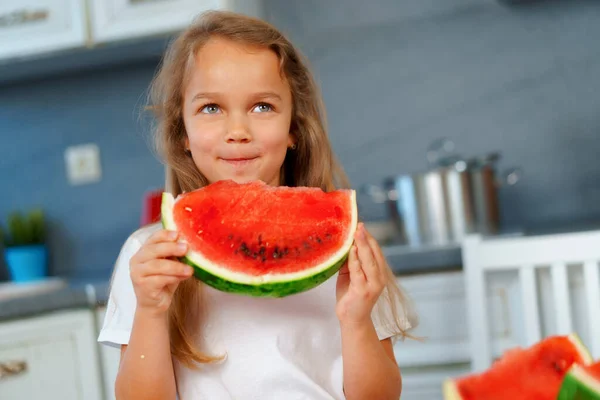 Little girl eating watermelon piece in the kitchen — Stock Photo, Image