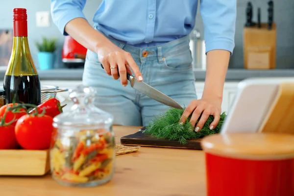 Jovem mulher branca loira cortando legumes para salada em sua cozinha — Fotografia de Stock