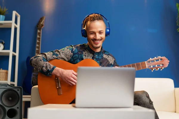 Jeune homme assis dans sa chambre et regardant tutoriel de guitare sur ordinateur portable — Photo