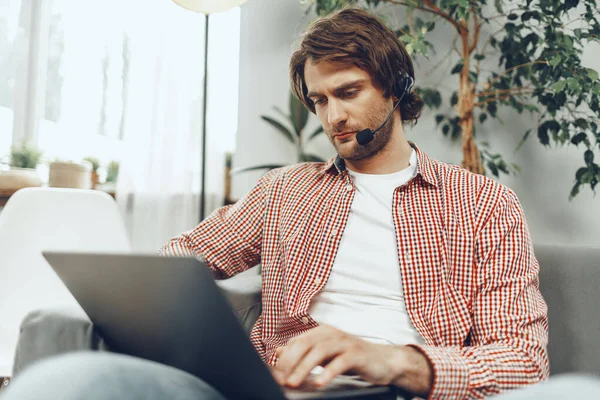 Kulaklık takan genç adam laptopla video görüşmesi yapıyor.