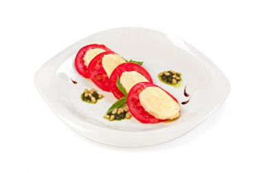 Dilimlenmiş, peynirli domates ve beyaza izole edilmiş otlar.