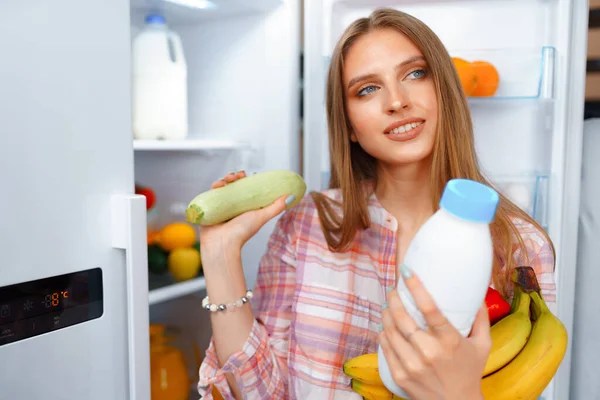 Retrato de una joven rubia tomando comida de su nevera — Foto de Stock