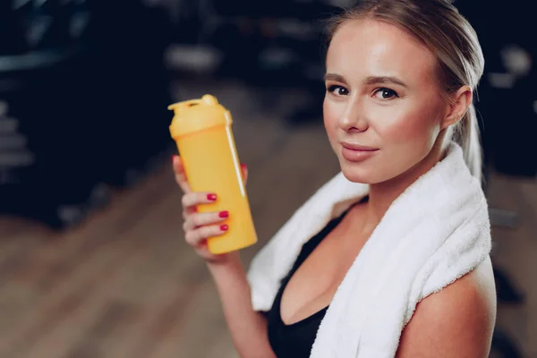 Ung sportig kvinna att ta en drink i ett gym efter träningen — Stockfoto