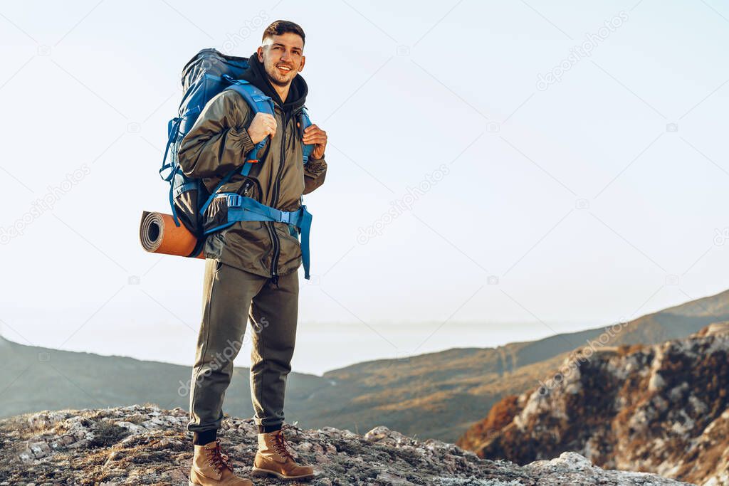 Young caucasian man traveler with big backpack hiking in the mountains