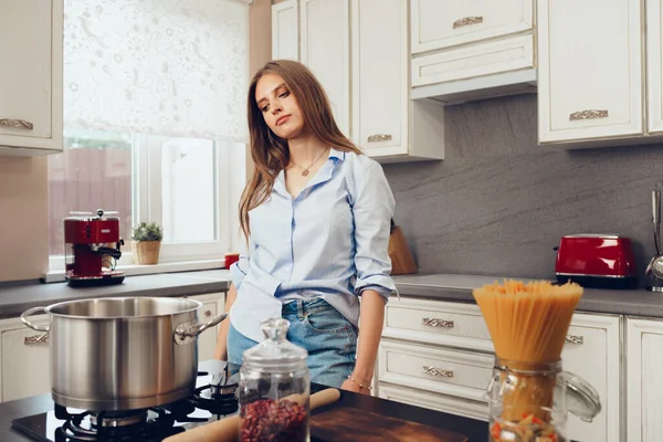 Pensive jovem mulher de pé na cozinha e pensando no que cozinhar — Fotografia de Stock