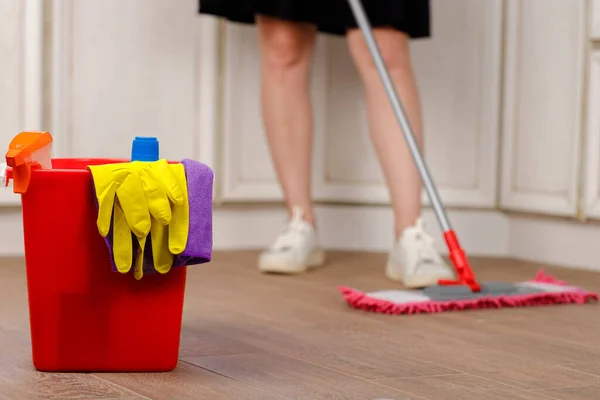 Woman washing floor with mop in kitchen