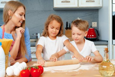 Anne ve küçük çocukları, kız ve erkek, mangırı hazırlamasına yardım ediyorlar.
