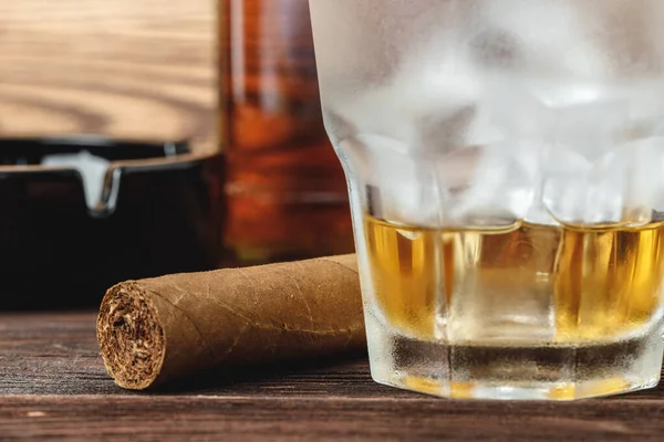 Стакан виски и сигары на деревянном столе — стоковое фото