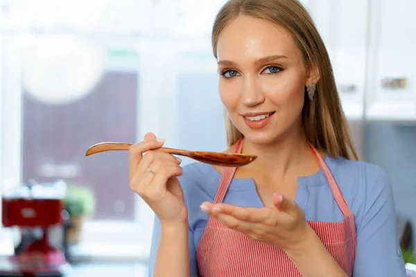 Привлекательная молодая блондинка проверяет приготовленную еду — стоковое фото