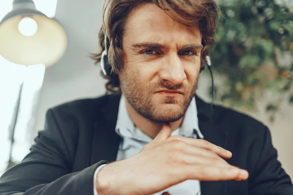 Close up portrait of an angry businessman with headset having stressful online conversation — Stock Photo, Image