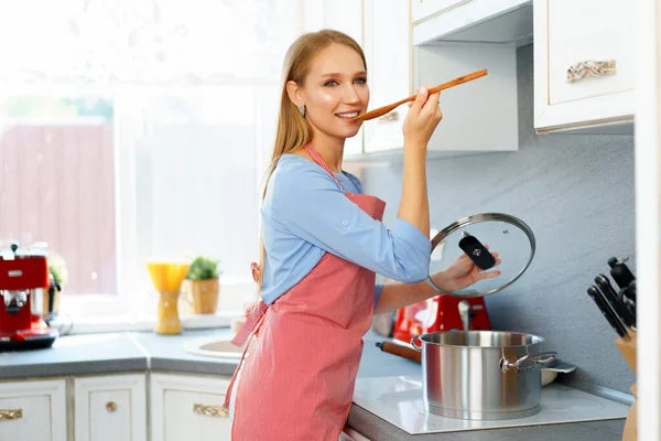 Atractiva joven rubia revisando comida cocinada —  Fotos de Stock