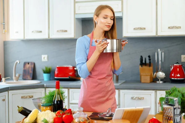 Mulher loira jovem atraente verificando alimentos cozidos — Fotografia de Stock
