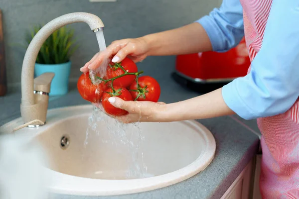 Close up photo of woman washing tomatoes in a sink