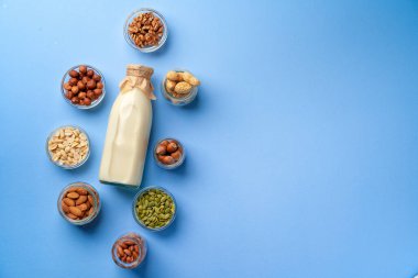 Süt şişeli sebze sütü kavramı ve mavi arka plan görünümlü tahıllı kaseler.