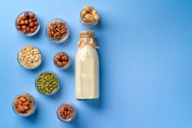 Süt şişeli sebze sütü kavramı ve mavi arka plan görünümlü tahıllı kaseler.