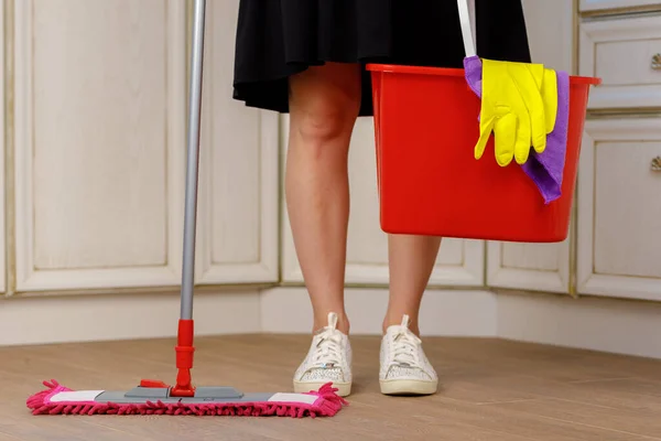 Woman washing floor with mop in kitchen