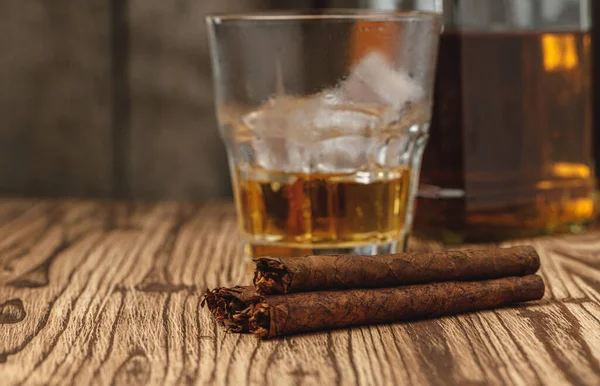 Verre de whisky et cigares roulés sur table en bois — Photo