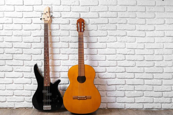 白いレンガの壁に向かって床にギターのセット — ストック写真