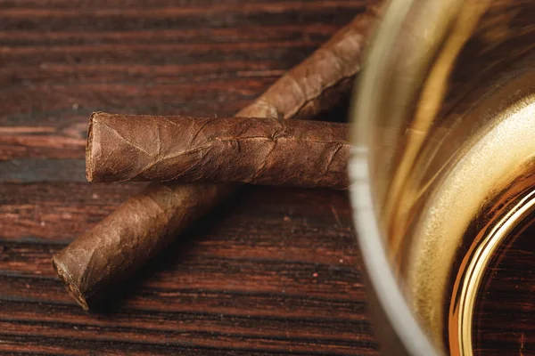 Glass of whiskey and rolled cigars on wooden table — Stock Photo, Image