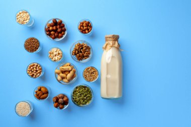 Süt şişeli sebze sütü kavramı ve mavi arka plan görünümlü tahıllı kaseler.