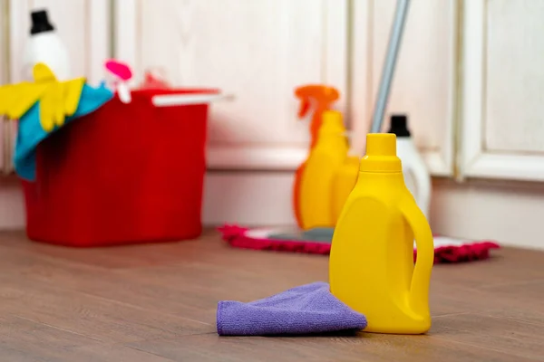 Varios detergentes y botellas de limpieza doméstica en un cubo de plástico en el suelo — Foto de Stock