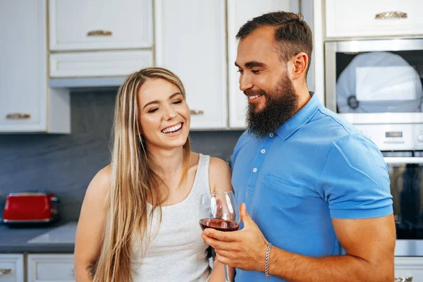 Alegre casal sorrindo cozinhar e beber vinho na cozinha — Fotografia de Stock
