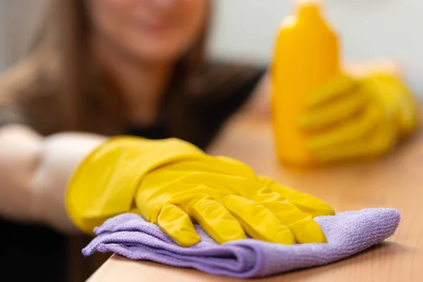 Nierozpoznawalna kobieta w żółtych rękawiczkach wycierająca drewniany blat stołu — Zdjęcie stockowe