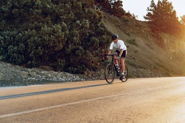 Gündoğumunda dağ yolunda profesyonel bisikletçi.