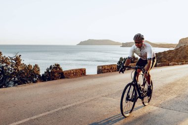 Bisikletli bir adam gün batımında açık havada bisiklet sürüyor.