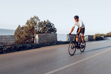 Bisikletli bir adam gün batımında açık havada bisiklet sürüyor.