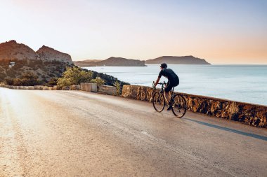 Kıyı yolunda bisiklet süren sporcu.