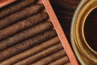 Ahşap masada rulo puro sarılı kırmızı tahta kutu. Yaklaş.