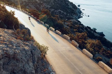 Bisikletli, sahil yolunda bisiklete biniyor.