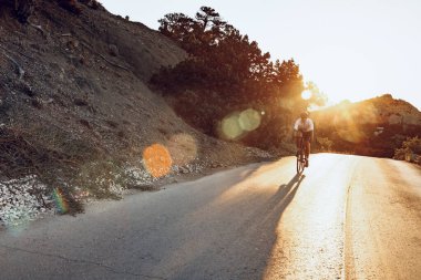 Bisikletli, sahil yolunda bisiklete biniyor.