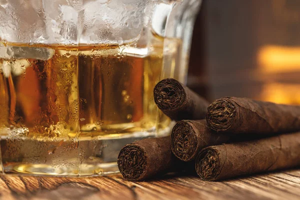 Vaso de whisky y cigarros enrollados en mesa de madera — Foto de Stock