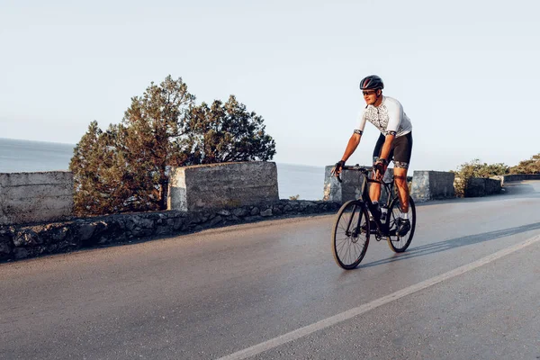 Bisikletli bir adam gün batımında açık havada bisiklet sürüyor.